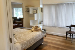 The main bedroom, with polished timber floor and a queen bed, at Spring Beach Holiday House.